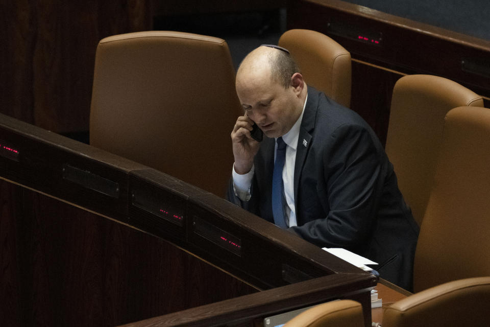 Israeli Prime Minister Naftali Bennett makes a call before voting on a law on the legal status of Jewish settlers in the occupied West Bank, during a session of the Knesset, Israel's parliament, in Jerusalem, Monday, June 6, 2022. (AP Photo/ Maya Alleruzzo)