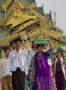 In this April 8, 2014 photo, a Buddhist devotee with a basket of offerings on her head leads a group of men to circumambulate the Shwedagon pagoda, ahead of their ordination as Buddhist monks, Yangon, Myanmar. Though most them only remain monks for a few days, ordination is seen as a right of passage in this predominantly Buddhist nation of 60 million. In addition to learning the basic tenants of their faith, it serves as a sort of spiritual credit for their parents, helping emancipate them from a viscous cycle of rebirth and death. (AP Photo/Gemunu Amarasinghe)