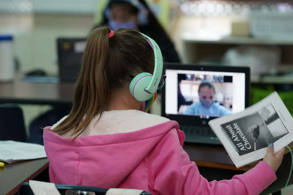 FILE - Students at Driggers Elementary School attend a class in-person as they interact with classmates virtually, Monday, Feb. 8, 2021, in San Antonio. The return to classrooms for the nation’s schoolchildren has not meant a return to work for many of their parents who, with workdays that outlast school days, are finding crucial afterschool programs in short supply. (AP Photo/Eric Gay, File)