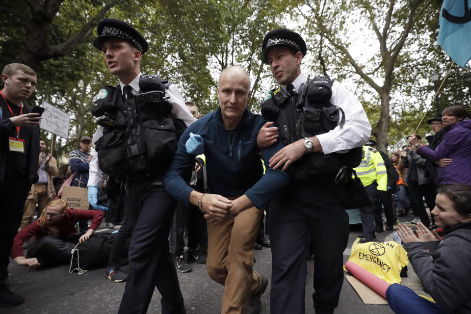 Police officers lead a handcuffed protestor away after climate protestors blocked a road in central London Monday, Oct. 7, 2019. (Photo: Matt Dunham/AP)