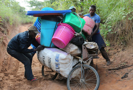 Congolese migrants expelled from Angola attempt to push a rented bicycle to transport their belongings along the dirt road to Tshikapa, Kasai province near the border with Angola, in the Democratic Republic of the Congo, October 12, 2018. REUTERS/Giulia Paravicini