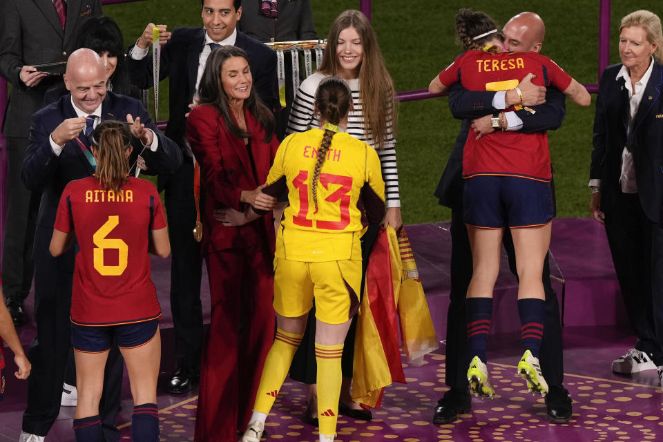 President of Spain's soccer federation, Luis Rubiales, right, embraces Teresa Abelleira on the podium following Spain's win in the final of Women's World Cup soccer against England at Stadium Australia in Sydney, Australia, Sunday, Aug. 20, 2023. Pictured from left, is FIFA President Gianni Infantino with Aitana Bonmati, Queen Letizia of Spain with reserve goalkeeper Enith Salon as Princess Infanta Sofia watches. (AP Photo/Mark Baker)