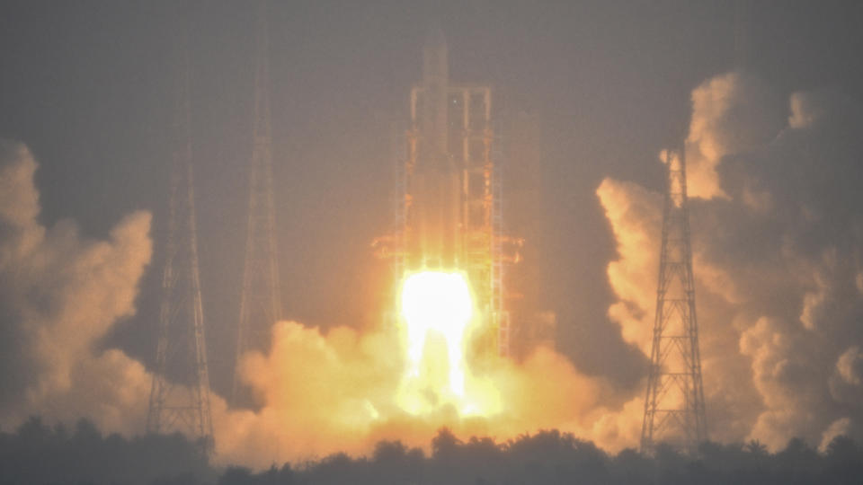 A Large White Rocket Launches Above A Plume Of Fire And Smoke. Heavy Fog Partially Obscures The View