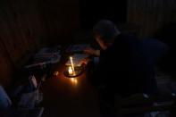 A man writes by candlelight as his neighbourhood Parque Batlle goes without electricity after a massive blackout in Argentina, in Montevideo