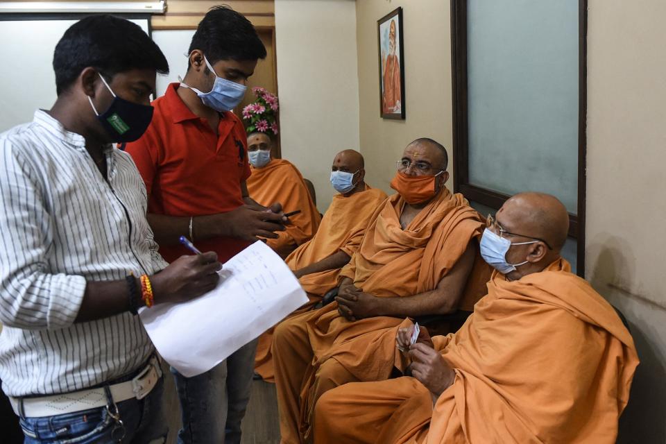 Los trabajadores de la salud toman los datos de contacto de los Sadhus u hombres santos hindúes antes de inocularlos con una vacuna contra el coronavirus en el Hospital BAPS Yogiji Maharaj, en Ahmedabad, la India, el 4 de marzo de 2021