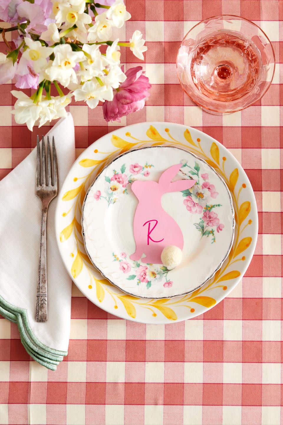 bunny shape placecard made from pink paper with a pom pom tail set on a plate