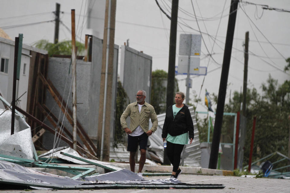 Tourists walk past debris littering the street after Hurricane Zeta's landfall in Playa del Carmen, Mexico, early Tuesday, Oct. 27, 2020. Zeta is leaving Mexico’s Yucatan Peninsula on a path that could hit New Orleans Wednesday night. (AP Photo/Tomas Stargardter)