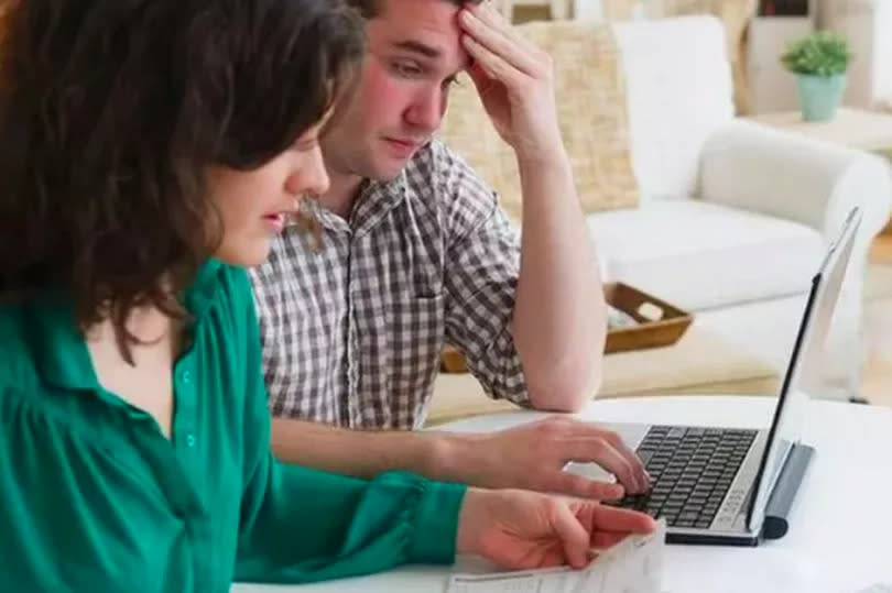 A man and woman are seated at a table looking at a computer screen