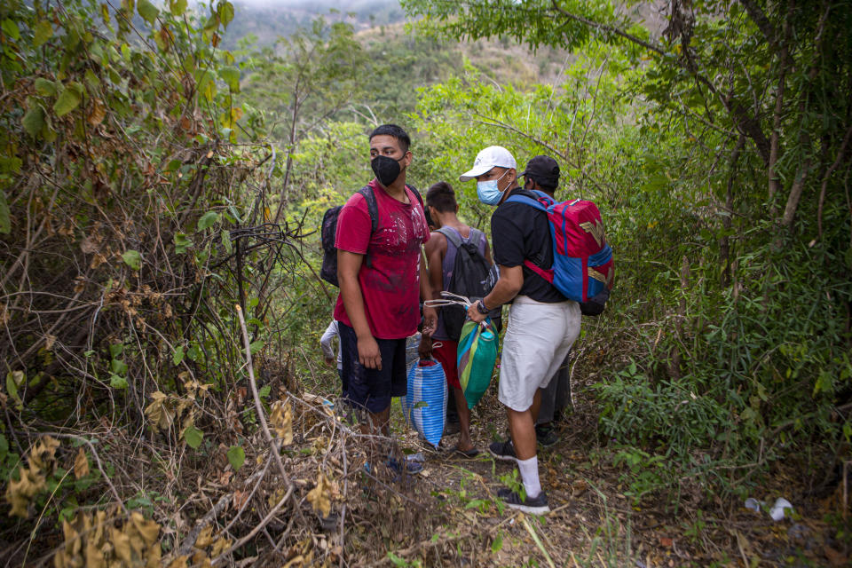 Honduran migrants observe a police checkpoint as they take an alternative route to avoid being detained in Chiquimula, Guatemala, Tuesday, Jan. 19, 2021. A once large caravan of Honduran migrants that pushed its way into Guatemala last week had dissipated by Tuesday in the face of Guatemalan security forces. (AP Photo/Oliver de Ros)