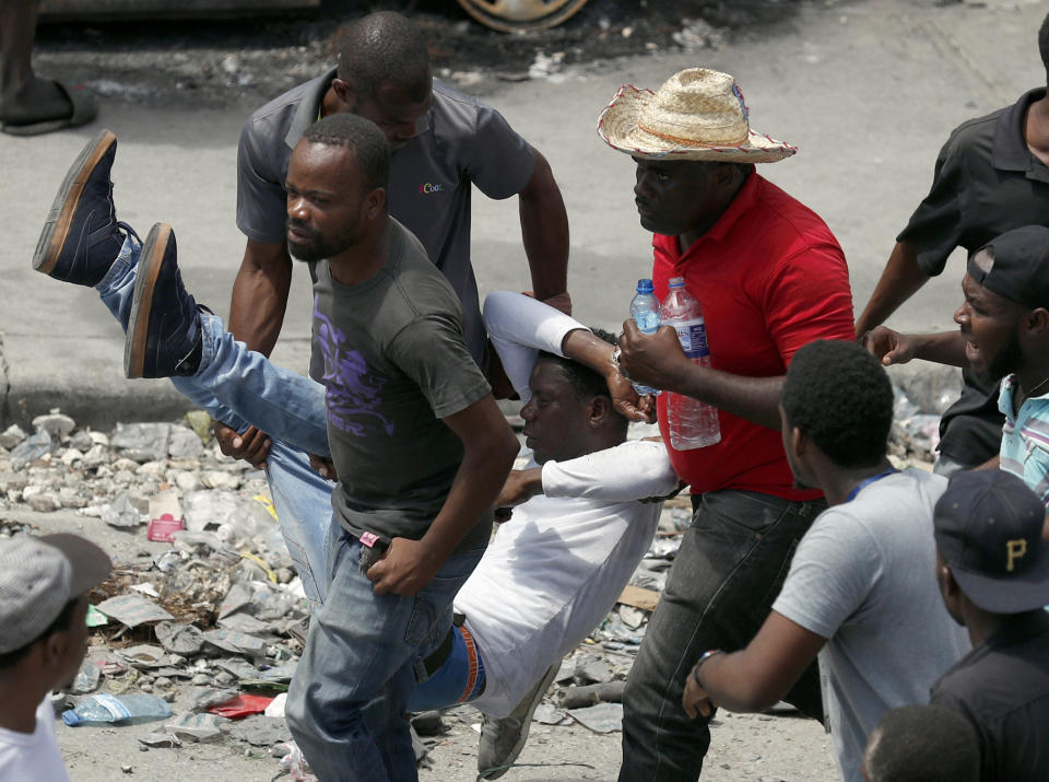 An injured demonstrator is carried to safety during a protest calling for the resignation of President Jovenel Moise, in Port-au-Prince, Haiti, Friday, Oct. 4, 2019. After a two-day respite from the recent protests that have wracked Haiti's capital, opposition leaders urged citizens angry over corruption, gas shortages, and inflation to join them for a massive protest march to the local headquarters of the United Nations.(AP Photo/Rebecca Blackwell)