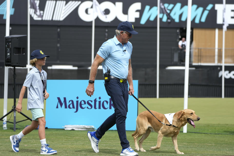 LIV Golf CEO Greg Norman, center, walks with his dog on the final day of the LIV Golf Team Championship at the Trump National Doral golf club, Sunday, Oct. 22, 2023, in Doral, Fla. (AP Photo/Lynne Sladky)