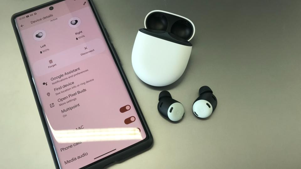 Google Pixel Buds Pro next to a Google Pixel 6 Pro smartphone on silver background