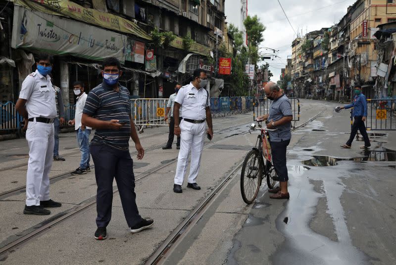 Police officers check travel permission papers of a man during the two-day weekly lockdown in the West Bengal state, amidst the spread of the coronavirus disease in Kolkata