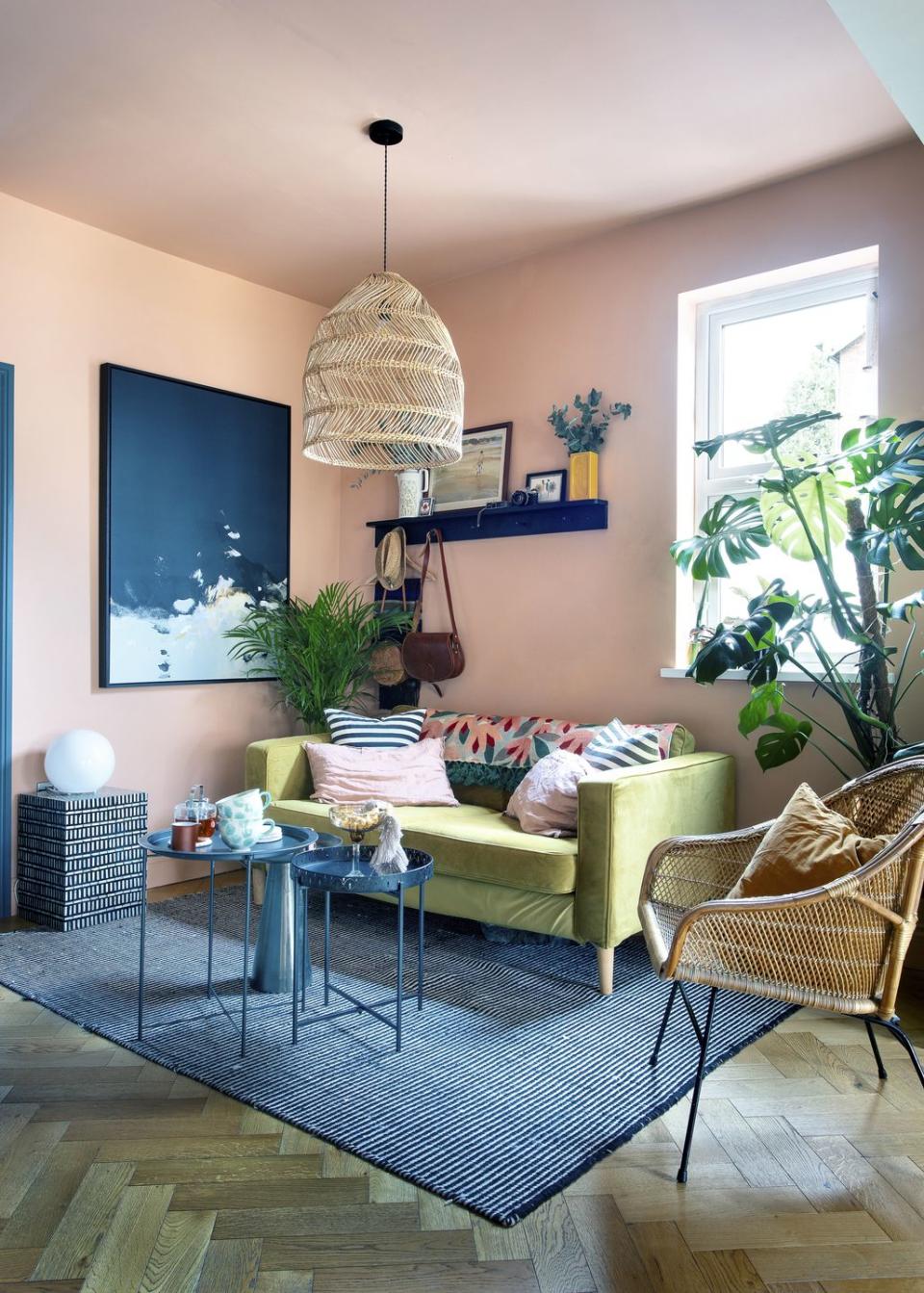 a cosy corner in the open plan kitchen with pale pink walls and an olive sofa