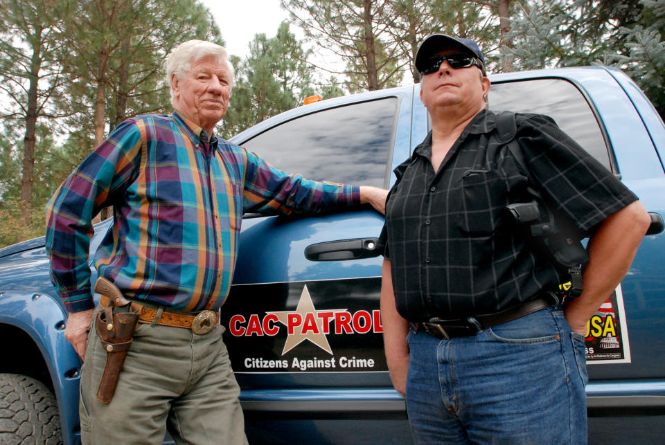 In this Oct. 12, 2012, photo, Sam Nichols, left, and Glenn Woodbury pose in front of Woodbury's pickup in O'Brien, Ore. The two men are part of a newly-formed neighborhood watch that does armed patrols around the rural area to deter crime since budget cutbacks have left the Josephine County Sheriff's Office with just three patrol deputies and limited jail space. (AP Photo/Jeff Barnard)