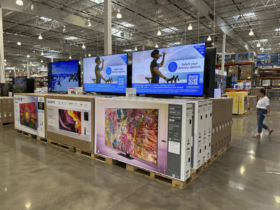 A shopper passes a display of televisions on sale in a Costco warehouse Thursday, June 22, 2023, in Colorado Springs, Colo. Analysts who follow the retail industry estimate that the resumption of student loan payments could trim consumer spending by $14 billion a month or $305 per borrower. (AP Photo/David Zalubowski)