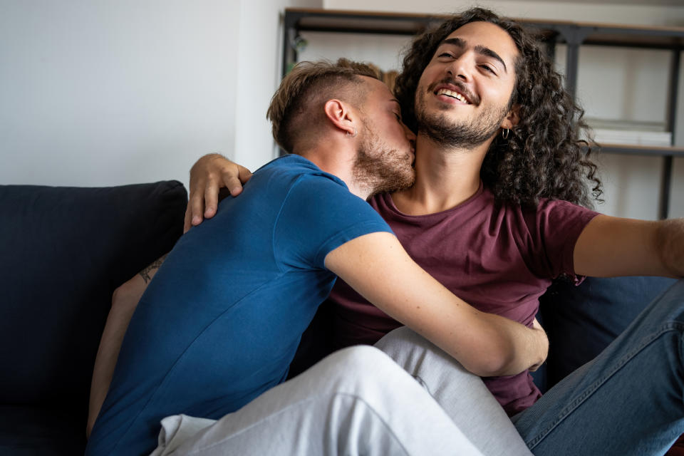 Two men embracing and sharing an affectionate moment on a sofa