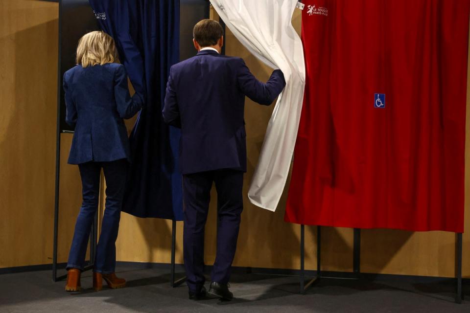 French President Emmanuel Macron and his wife Brigitte Macron enter a voting booth during the European elections on Sunday (AP)