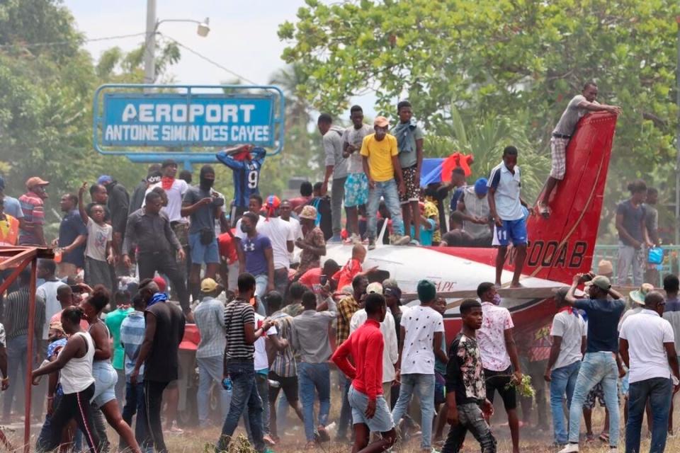 People gather on and around an airplane during a protest against insecurity and violence at the Antoine Simon Des Cayes airport in Les Cayes, Haiti, Tuesday, March 29, 2022. The protest coincides with the 35th anniversary of Haiti's 1987 Constitution and follows other protests and strikes in recent weeks in the middle of a spike in gang-related kidnappings.