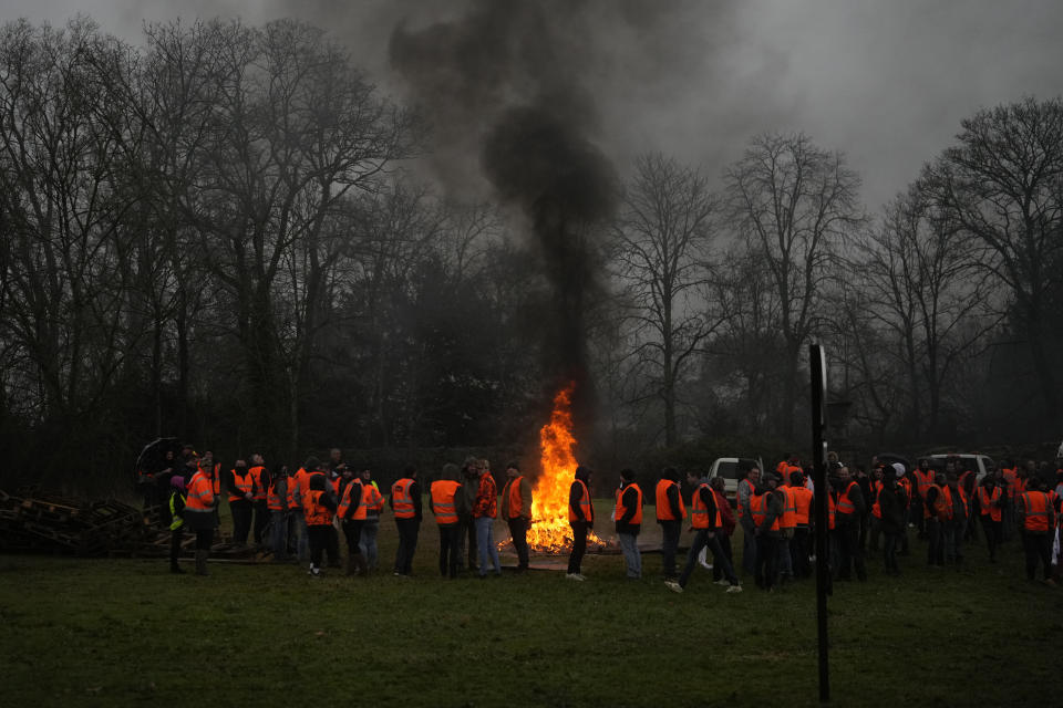 Farmers gather at a bonfire as they block a roundabout in Fontainebleau, south of Paris, Friday, Jan. 26, 2024 in Paris. Snowballing protests by French farmers crept closer to Paris with tractors driving in convoys and blocking roads in many regions of the country to ratchet up pressure for government measures to protect the influential agricultural sector from foreign competition, red tape, rising costs and poverty-levels of pay for the worst-off producers. (AP Photo/Thibault Camus)