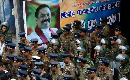 Members of Sri Lanka's Special Task Force and the police stand guard next to a poster of newly appointed Prime Minister Mahinda Rajapaksa after an official security guard of sacked minister Arjuna Ranatunga shot and wounded three people in front of the Ceylon Petroleum Corporation, in Colombo, Sri Lanka October 28, 2018. REUTERS/Dinuka Liyanawatte