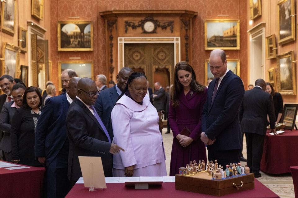 Prince William, Prince of Wales and Catherine, Princess of Wales escort Dr. Naledin Pandor, Minister of International Relations and Cooperation during a visit to view items, including a a chess set, which was a gift from President Mandela to the Duke of Edinburgh in 1996, displayed as part of the Royal Collection at Buckingham Palace