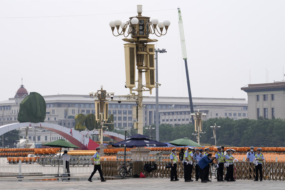 Traffic policemen gather near a photographer taking photos near the Tiananmen Square in Beijing on Wednesday, June 23, 2021. Chinese authorities have closed Beijing's central Tiananmen Square to the public, eight days ahead of a major celebration being planned to mark the 100th anniversary of the founding of the ruling Communist Party. (AP Photo/Andy Wong)