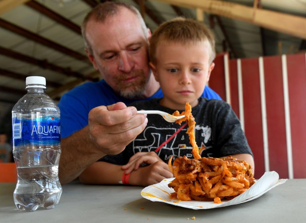 John Carone holds on to his son, Wyatt, as he eats fries lathered in chili at the Ventura County Fair in 2022.