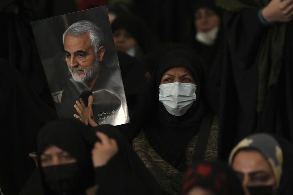 A mourner holds a poster of the late Revolutionary Guard Gen. Qassem Soleimani, who was killed in Iraq in a U.S. drone attack in 2020, during a ceremony marking anniversary of his death, at Imam Khomeini Grand Mosque in Tehran, Iran, Tuesday, Jan. 3, 2023. Iran's President Ebrahim Raisi on Tuesday vowed to avenge the killing of the country's top general on the third anniversary of his death, as the government rallied its supporters in mourning amid months of anti-government protests. (AP Photo/Vahid Salemi)