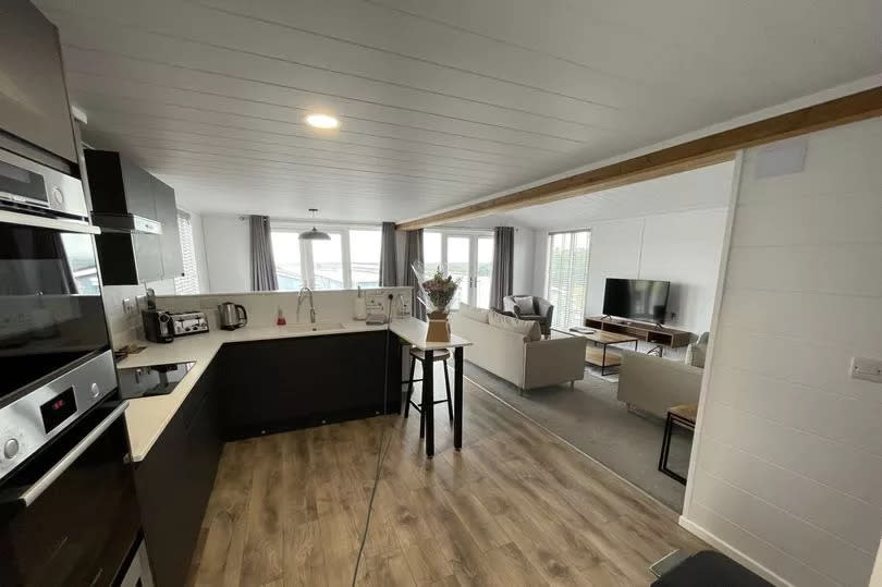 Open-plan lounge kitchen diner with a duo of French doors to the deck