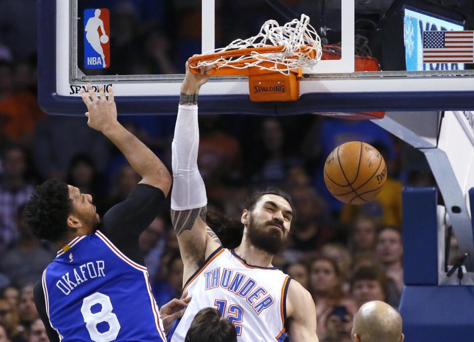 Oklahoma City Thunder center Steven Adams (12) dunks in front of Philadelphia 76ers center Jahlil Okafor (8) during the first quarter of an NBA basketball game in Oklahoma City, Wednesday, March 22, 2017. (AP Photo/Sue Ogrocki)