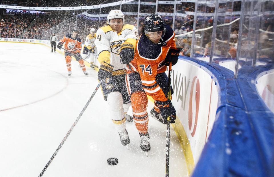 Nashville Predators' Mikael Granlund (64) and Edmonton Oilers' Ethan Bear (74) battle for the puck during third-period NHL hockey game action in Edmonton, Alberta, Saturday, Feb. 8, 2020. (Jason Franson/The Canadian Press via AP)