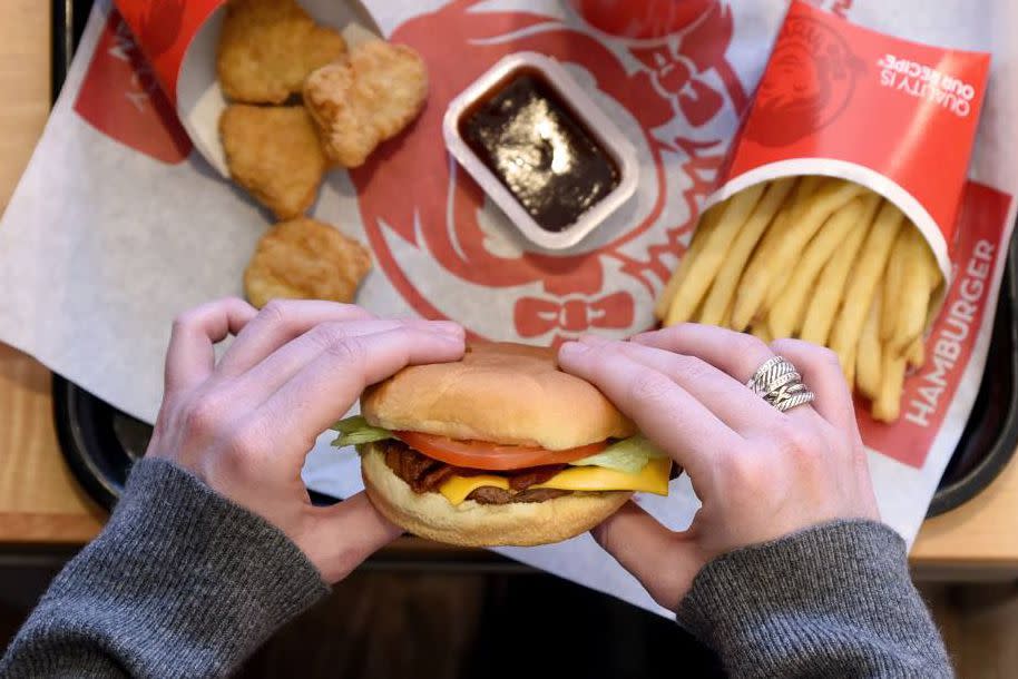 hands holding burger, other menu items in background