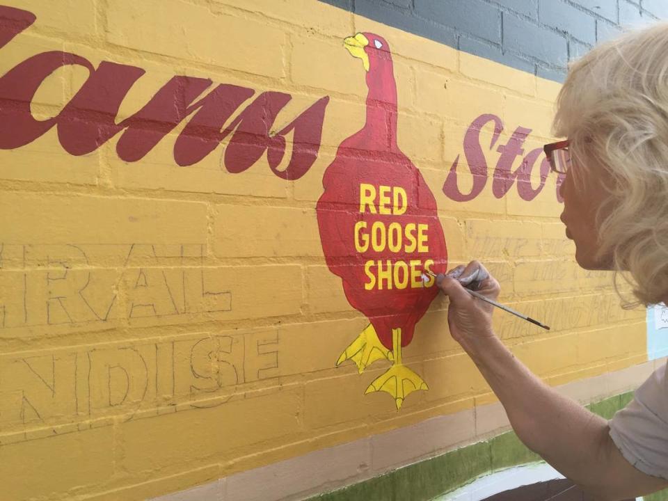 An artist paints detail on the “Bullet” Bob Turley mural to represent the shoe store that once occupied the Adams Store building in Troy. The mural was completed in 2015.