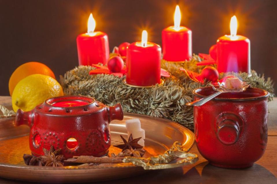 Little Feuerzangenbowle in red ceramic pot with the burning sugar on the absinthe spoon on the black Background horizontal