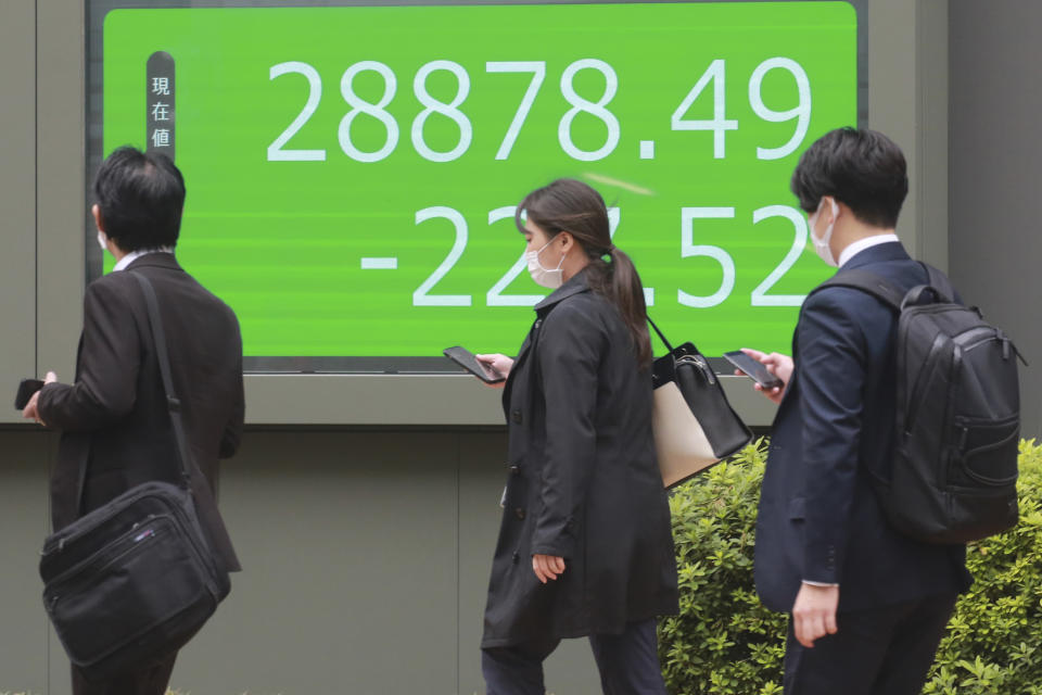 People walk by an electronic stock board of a securities firm in Tokyo, Wednesday, Oct. 27, 2021. Asian stock markets fell Wednesday after Australian inflation increased, highlighting global pressure for prices to rise, while investors looked ahead to U.S. economic growth data due out this week. (AP Photo/Koji Sasahara)