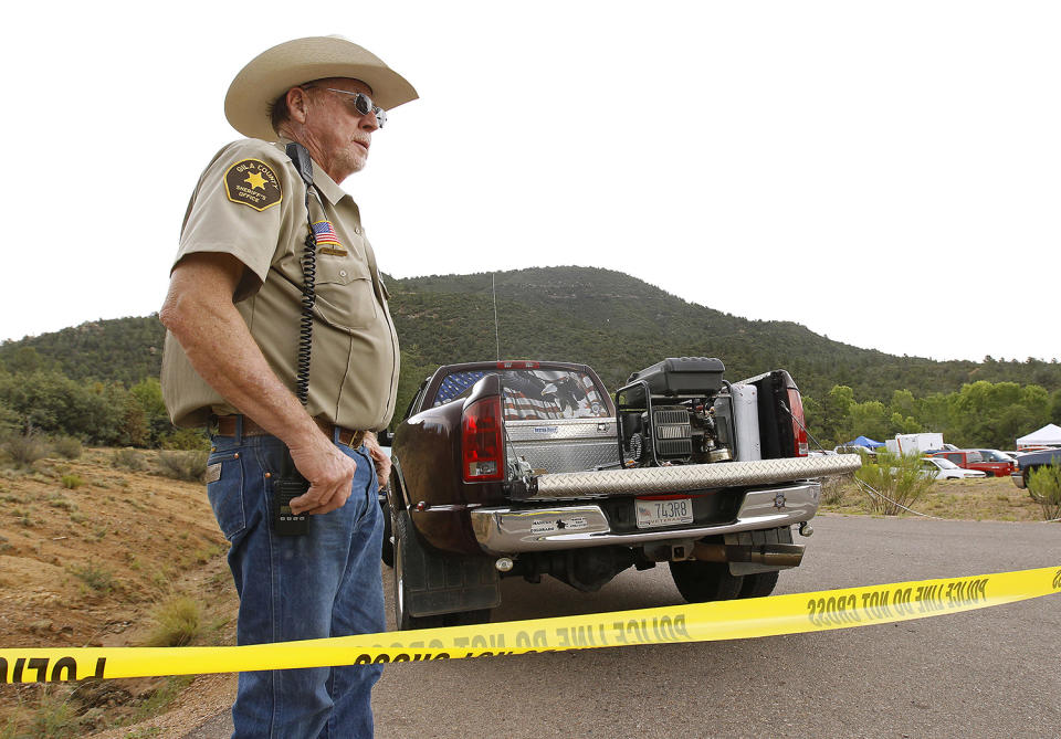 <p>Gila County Sheriff’s Office deputy Larry Hassinger stands watch at the entrance to the First Crossing recreation area during a search and rescue operation for victims of a flash flood along the banks of the East Verde River, Sunday, July 16, 2017, in Payson, Ariz. (AP Photo/Ralph Freso) </p>