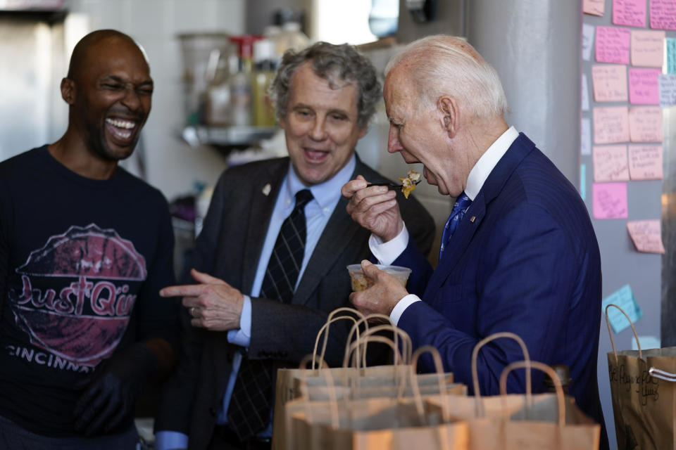 FILE - Sen. Sherrod Brown, D-Ohio, and Just Q'in BBQ owner Matthew Cuff talk with President Joe Biden as he eats peach cobbler during a visit to Just Q'in BBQ in Cincinnati, Jan. 4, 2023. Brown has survived a decade of statewide Democratic losses in Ohio by building a reputation as the rare person in his party who can still connect with the white working-class voters who have increasingly shifted to Republicans. But as he heads into what could be a tough reelection, Brown is facing a critical test in the aftermath of a train derailment in an eastern Ohio village. (AP Photo/Patrick Semansky, File)