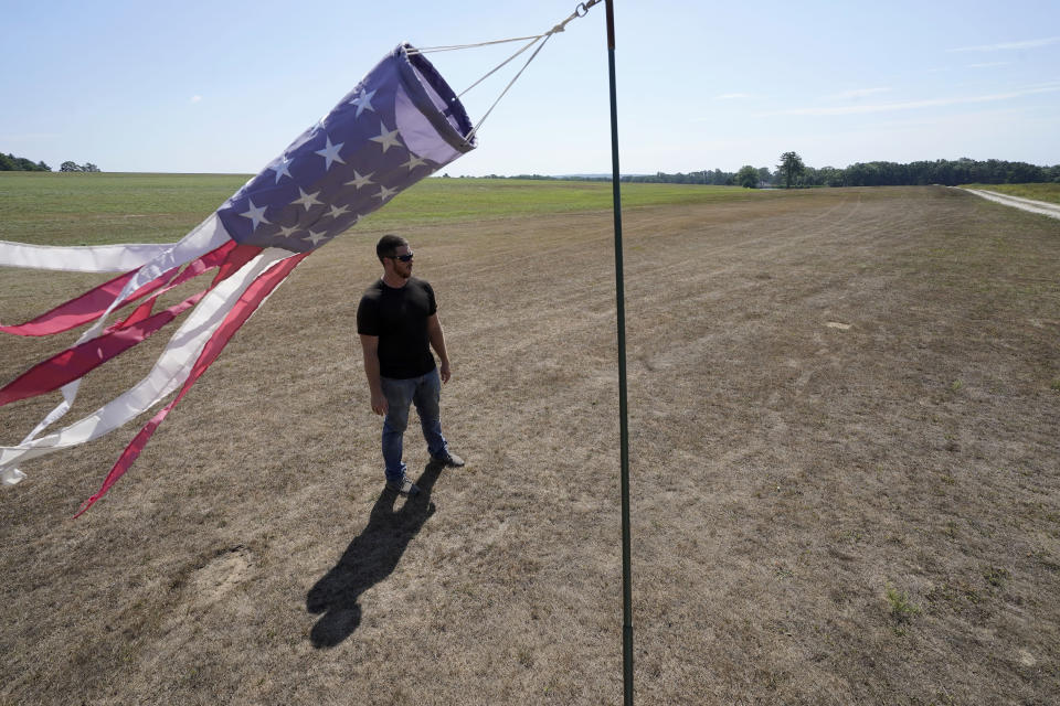 FILE — Hay farmer Milan Adams stands in a dry hay field near a wind sock, in Exeter, R.I., Tuesday, Aug. 9, 2022. Adams said in prior years it rained in the spring. This year, he said, the dryness started in March, and April was so dry he was nervous about his first cut of hay. Arid conditions in the northeastern U.S. have benefited amusement parks, minor league baseball teams, construction contractors and other businesses that need warm, dry weather to attract paying customers and get jobs completed on time. (AP Photo/Steven Senne, File)