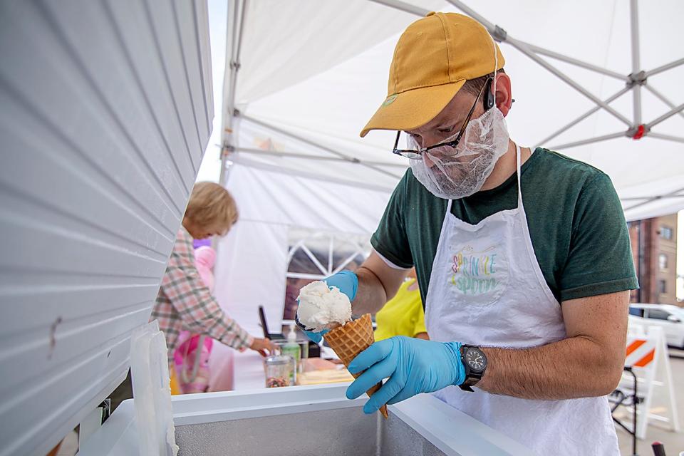 Gabriel Wynkoop serves up a scoop of ice cream at the Sprinkle & Spoon vendor stand at Galesburg's Cafe in the Park on Wednesday, Aug. 18, 2021 in Park Plaza.