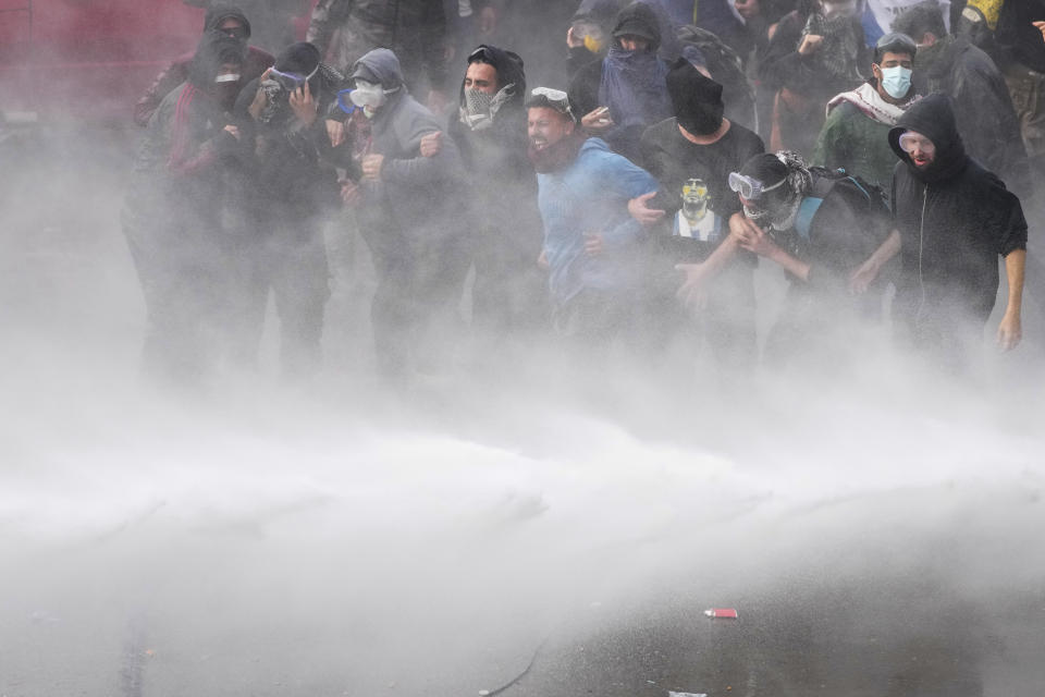 Anti-government protesters are sprayed by a police water cannon outside Congress as lawmakers debate a reform bill promoted by Argentine President Javier Milei in Buenos Aires, Argentina, Wednesday, June 12, 2024. (AP Photo/Natacha Pisarenko)