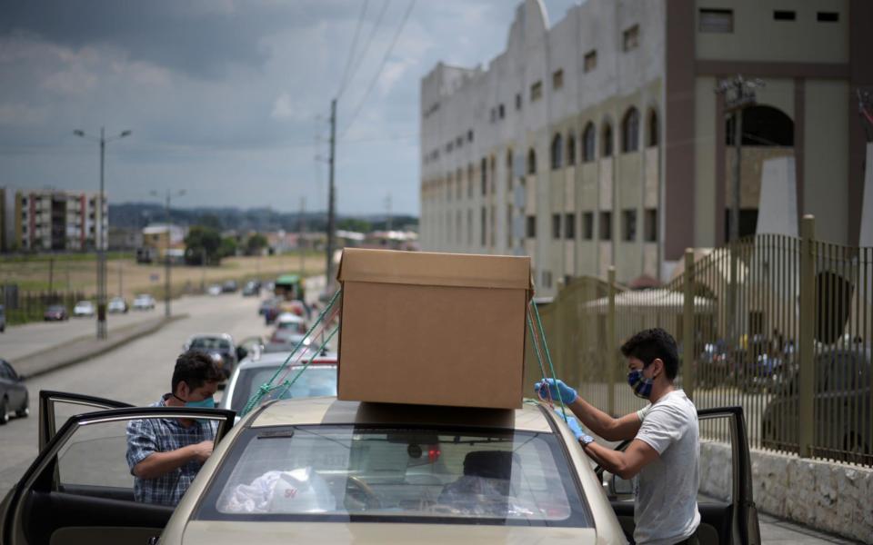 People tie an empty cardboard box on the roof of a car outside a cemetery last April, when a surge in Covid cases sparked a shortage of coffins, in Guayaquil - REUTERS/Vicente Gaibor del Pino