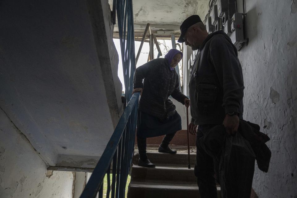 FILE - A volunteer helps Olha Faichuk, 79, down the stairs from her apartment, which was heavily damaged by a Russian airstrike, in Lukiantsi, Kharkiv region, Ukraine, on Tuesday, April 16, 2024. (AP Photo/Evgeniy Maloletka, File)