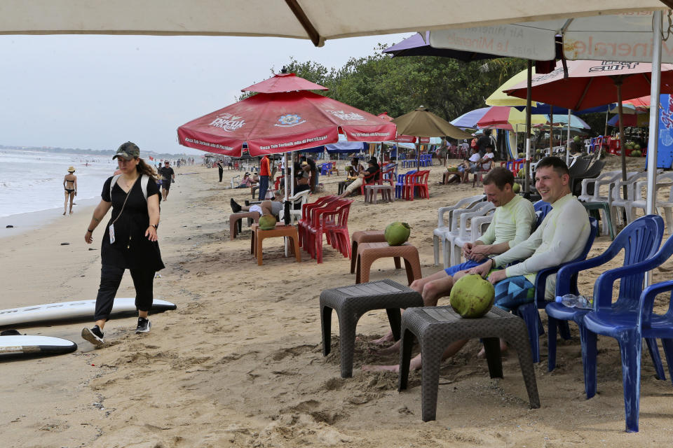 Tourists sit on a beach in Bali, Indonesia on Saturday, Nov. 12, 2022. The dozens of world leaders and other dignitaries traveling to Bali for the G-20 summit will be drawing a welcome spotlight on the revival of the tropical island's ailing tourism sector. Bali's economy is on the mend but it's still drawing only a third of the travelers who used to arrive here before the pandemic. (AP Photo/Firdia Lisnawati)