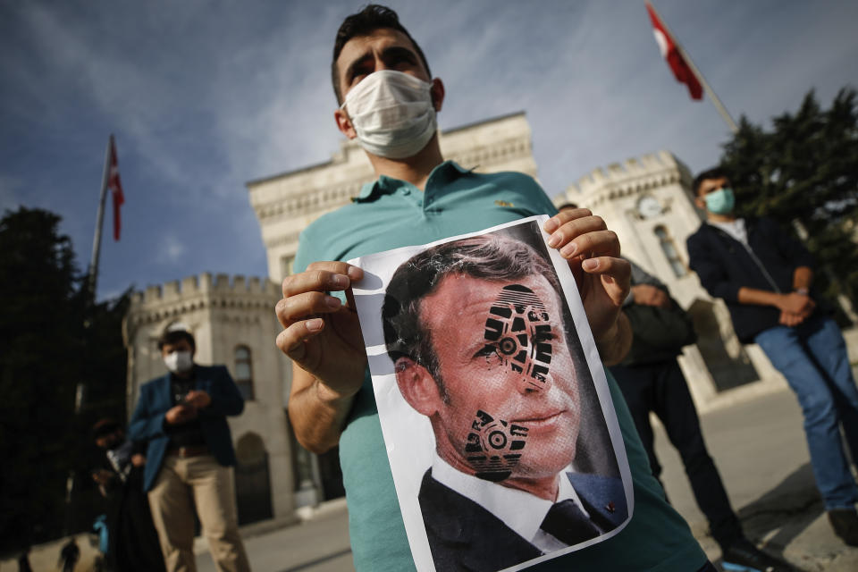 A youth holds a photograph of France's President Emmanuel Macron, stamped with a shoe mark, during a protest against France in Istanbul, Sunday, Oct. 25, 2020. Turkish President Recep Tayyip Erdogan on Sunday challenged the United States to impose sanctions against his country while also launching a second attack on French President Emmanuel Macron. Speaking a day after he suggested Macron needed mental health treatment because of his attitude to Islam and Muslims, which prompted France to recall its ambassador to Ankara, Erdogan took aim at foreign critics. (AP Photo/Emrah Gurel)