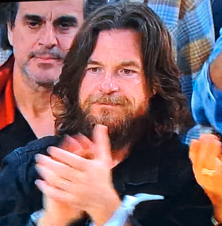 Closeup of Jason Bateman with shoulder-length hair and a very full beard