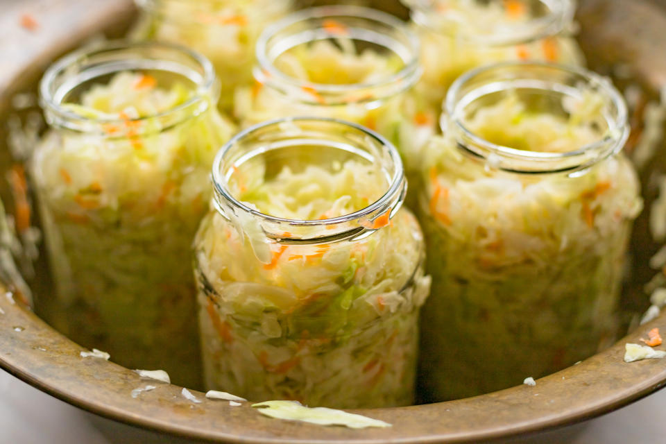 Sauerkraut fermentation in copper bowl, glass pot. Cut white cabbage fermented by lactic acid bacteria. Close up. Selective focus. Copy space