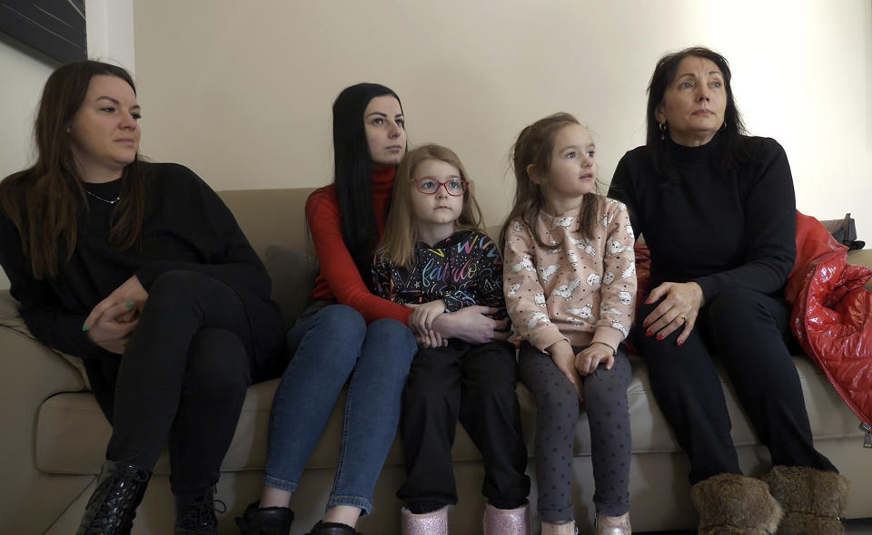 Lilia Kosovich, right, her daughter-in-law, Khrystyna Kosovich, left, and Iryna Kozoriz, second left, and her daughters Kamila and Anastasia, sit on a sofa during an interview with the Associated Press in Berlin, Germany, Tuesday, March 1, 2022. As Russia's war in Ukraine drags into its second week, more than 1.5 million Ukrainians immigrants living in other European countries, are watching on in agony, horror and fear as their relatives and friends back home are looking for shelter in bunkers or are desperately trying to flee the country. (AP Photo/Pietro De Cristofaro)