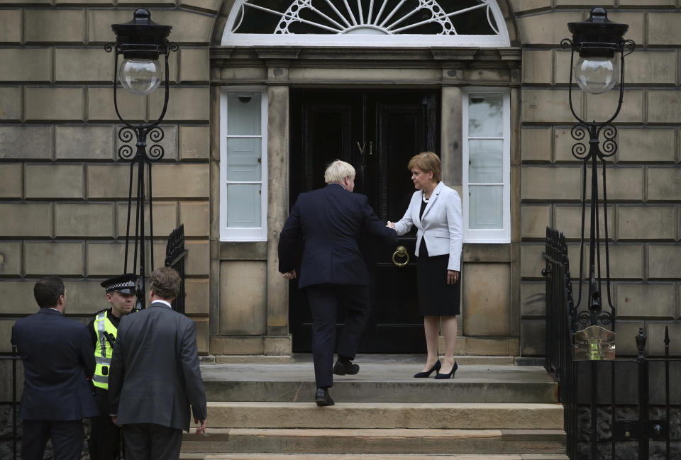 Scotland's First Minister Nicola Sturgeon, centre right, welcomes Britain's Prime Minister Boris Johnson, outside Bute House, ahead of their meeting, in Edinburgh, Scotland, Monday July 29, 2019. Johnson made his first official visit as British prime minister to Scotland, pledging to boost "the ties that bind our United Kingdom" amid opposition from Scottish leaders to his insistence on pulling Britain out of the European Union with or without a deal. (Jane Barlow/PA via AP)
