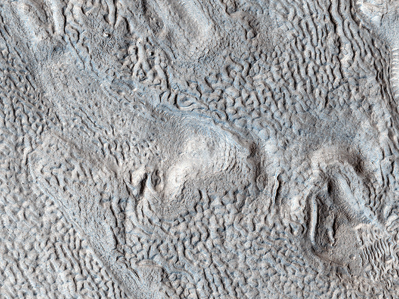 Long linear ridges and grooves curve, wave, and buckle across most of this image. Here, as elsewhere on Mars, these linear ridges and grooves fill a valley floor, hence their name, "lineated valley fill."  Because these features are only found in valleys in the middle latitudes (30 to 60 degrees) of the Northern and Southern hemispheres, scientists had long suspected that they were associated with some ancient climate that had prevailed in that latitudinal band. Based on peering beneath the surface using radar, scientists now think that lineated valley fill is probably merely a rocky veneer atop a glacier of nearly pure ice! The rocks that make up the linear ridges and grooves were oriented by the ancient flow of the glacier underneath.  (Caption: Ethan Schaefer)  